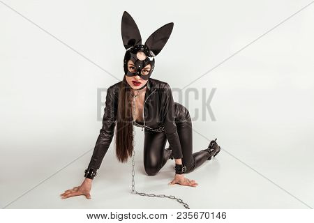 Kinky Woman In Sexy Costume In Submissive Position With Chain On Neck On White Background