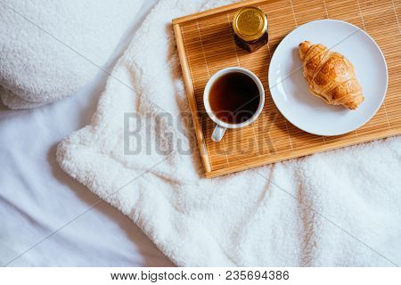 Big White Morning Cup Of Coffee, Crossant And Jam On The Wooden Tray In Bed With Pillow And Cosy Bla
