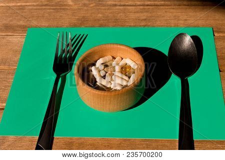A Lot Of Colorful Pills In A Plate On A Wooden Table . Fork And Spoon . The Concept Of A Healthy Lif