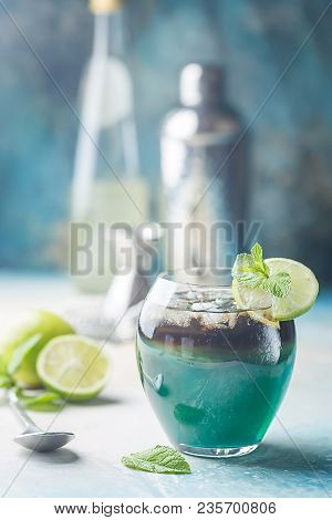 A Blue Layer Alcoholic Cocktail With Lime Over Blue Background