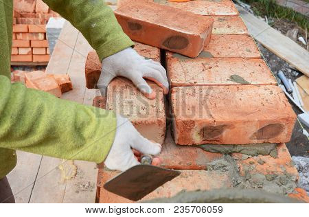 Bricklayers Hands In Masonry Gloves Bricklaying On House Construction Site. Bricklaying,  Brickwork.