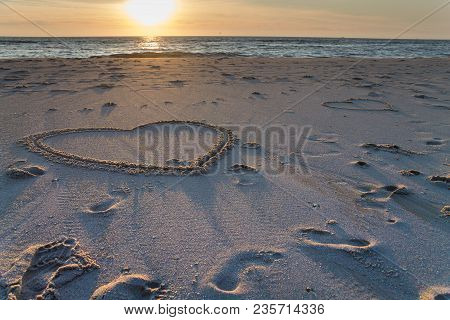 Beautiful Sunset At The Beach With Wooden Piles And Hearts Drawings In The Sand Petten, Holland, Nor