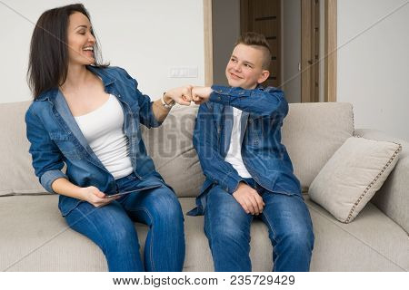 Happy Mother And Son Sitting On Sofa And Using Digital Tablet At Home