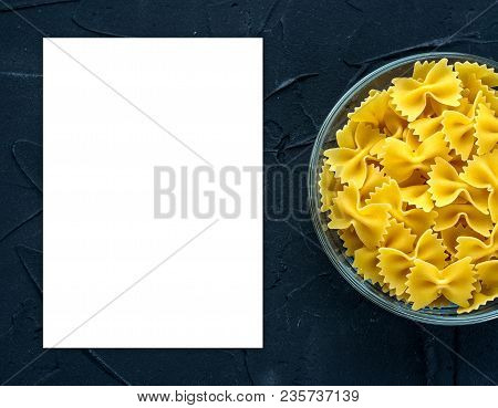 Farfalle Raw Pasta In A Glass Cup On A Black Textured Background From The Side. Close-up With The To
