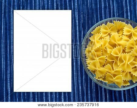 Farfalle Raw Pasta In A Glass Cup On A Striped White Blue Cloth Background With A Side. Close-up Wit