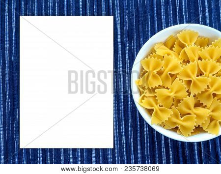 Farfalle Raw Pasta In A White Bowl On A Striped White Blue Cloth Background With A Side. Close-up Wi