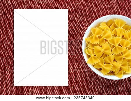 Farfalle Raw Pasta In A White Cup On A Red Brown Rustic Texture Background, In The Center Close-up F
