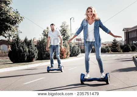 Lets Try Together. Satisfied Happy Young Married Couple Having Fun Riding On The Self-balancing Scoo