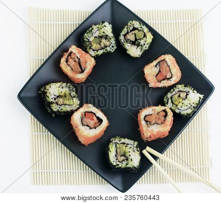 Different Types Of Maki Sushi On A Black Plate.isolated On White Background
