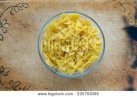 Farfalle Raw Farfallini Pasta In A Glass Bowl On A Wooden Cutting Board, Texture Background, In The 
