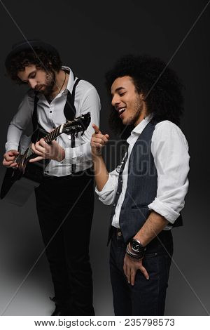 Young Duet Of Musicians Playing Guitar And Singing On Black