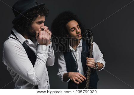 Duet Of Musicians Playing Acoustic Guitar And Harmonica On Black