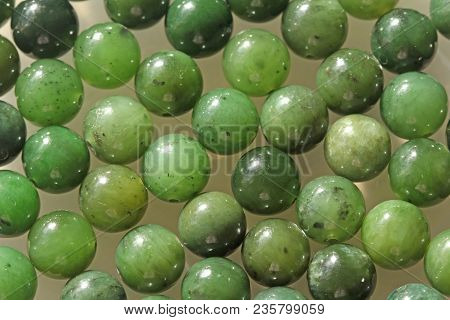 Natural Green Jade Nephrite Mineral Stones Beads. Green And Grassy Natural Background Made Of Round 
