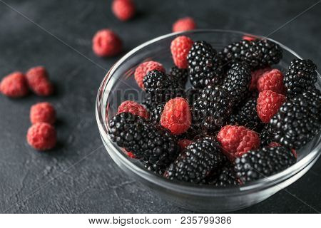 Glass Plate With Ripe Red Blackberries And Raspberries On A Black Surface. Macro Photo Of Ripe Black