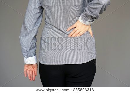 Close-up View Of A Young Woman With Pain In Kidneys Isolated On A Gray Background. Young Woman With 