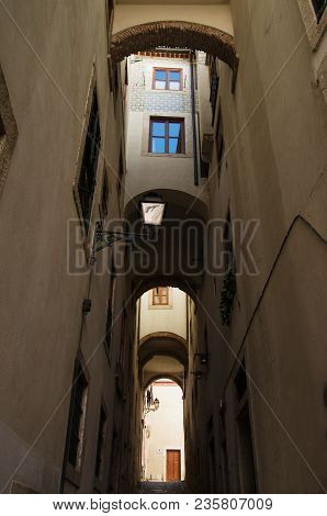 Walls And Windows Flanking, And Topping A Narrow And Tall Archway In Alfama Disctrict, The Most Famo
