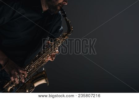 Cropped Shot Of Jazzman Playing Saxophone On Black