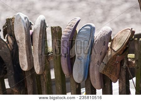 Old Worn House Slippers On Wooden Fence. Symbol Of Poor. The Concept Of Poverty