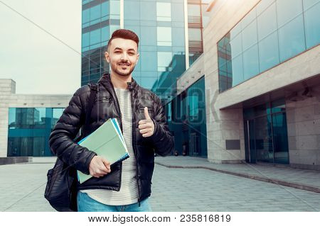 Arabian Student Showing Thumb Up Holding Copybooks By Modern University. Happy Young Man Successful 