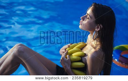 Woman With Tropical Fruit In Pool. Vitamin In Banana At Girl Sitting Near Water. Summer Vacation And