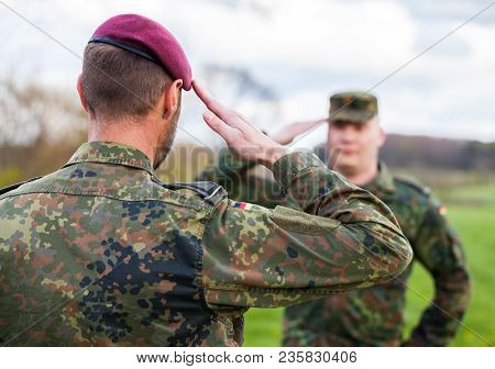 Two German Soldiers Salute Each Other On A Field