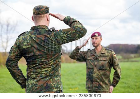 Two German Soldiers Salute Each Other On A Field