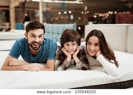 Lovely Bearded Man, Together With His Beautiful Wife And Son, Relaxes On The Mattress In The Store. 