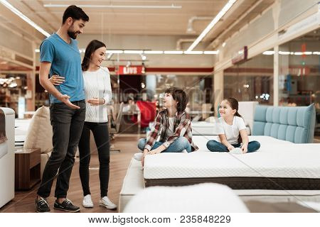 Happy Family With Children Came In Furniture Store To Buy Mattress. Young Couple With Happy Children