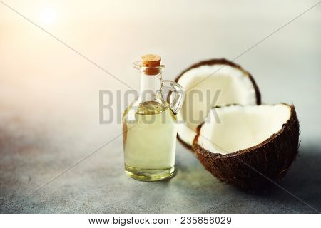 Cracked Two Halves Of Fresh Organic Coconut And Coconut Oil On Grey Background. Copy Space.