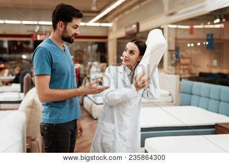 Lovely Girl Consultant Demonstrates Orthopedic Mattress To Confident Man In Furniture Store. Purchas
