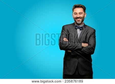 Middle age man, with beard and bow tie with crossed arms confident and happy with a big natural smile laughing