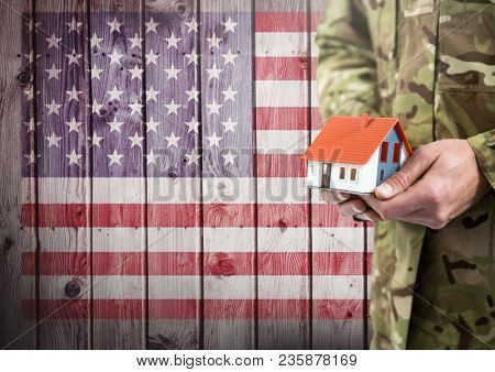 Close up of soldier holding a little house in front of american flag