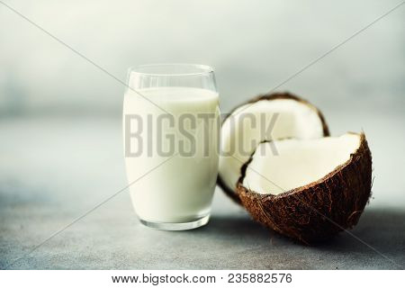 Coconut Vegan Milk Non Dairy In Glass And Coconut Fuit Halves On Grey Concrete Background With Copy 