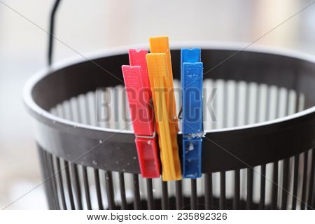 A Three Colorful Clothes Pegs Attached To A Small Bucket