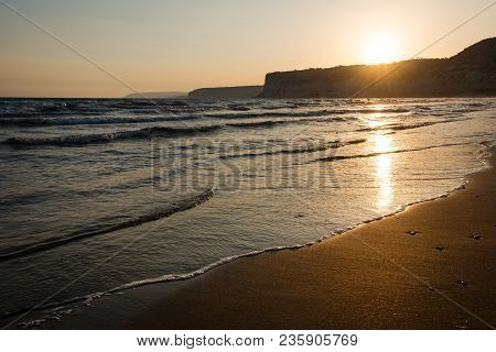 Waves Approaching Sandy Beach During The Sunset