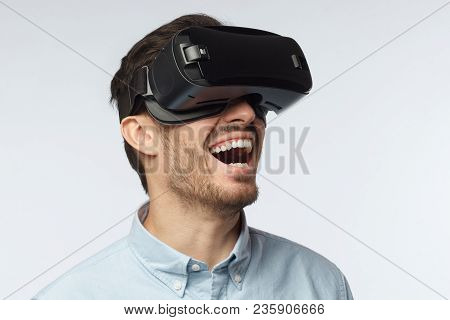 Young Man With Bristle In Blue Shirt, Wearing Virtual Reality Glasses, Lauthing At Loud, Looking To 