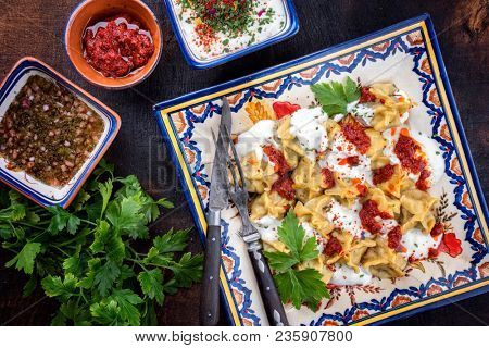 Traditional Turk manti steamed with mincemeat and paprika tomato salad as top view on a plate