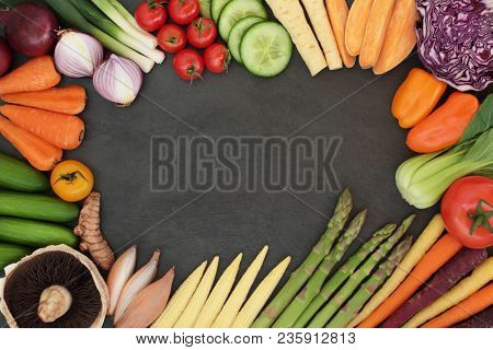 Fresh vegetable superfood border with health food high in antioxidants, anthocyanins, vitamins, minerals and  fiber, on slabe background. 