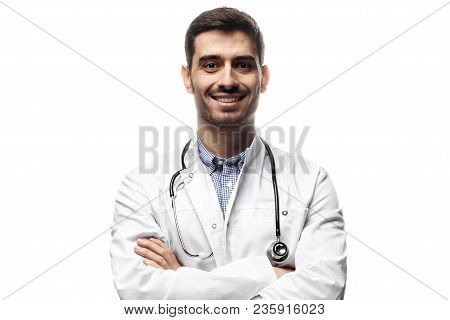 Closeup Shot Of Young Caucasian Man Doctor Standing With Crossed Arms In White Uniform Against White