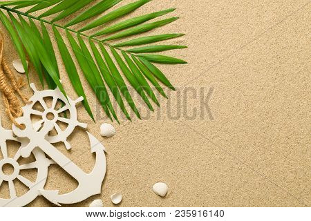 Summer Background With Decorative Anchor And Ship Steering Wheels. Sandy Beach Texture. Copy Space. 