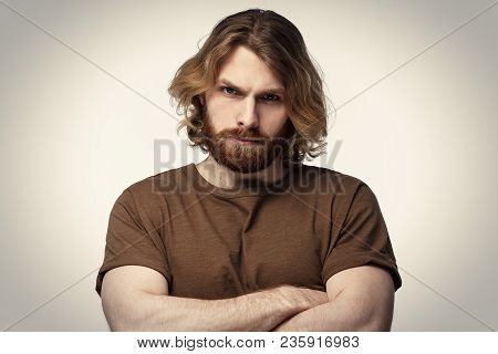 Tough Masculine Bearded Guy Standing With Crossed Arms Isolated On Grey Background. Serious Young Ma