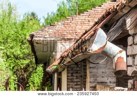 Old Rain Gutter. Old And Rusty Rain Gutter On Abandoned House Damaged By Age And Water Close Up