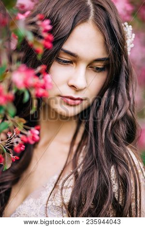 Close Up Portrait Of Beautiful Young Brunette Woman Outdoors Next To Sakura, Looking Down