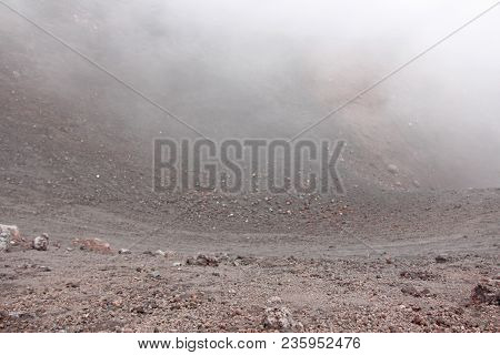 The Etna Volcano. Black Volcanic Earth And Thick Fog On Mount Etna. Place For Text. The Island Of Si