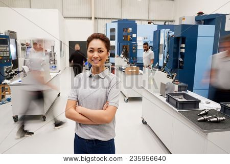 Portrait Of Female Engineer On Factory Floor Of Busy Workshop