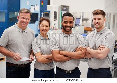 Portrait Of Engineering Team On Factory Floor Of Busy Workshop