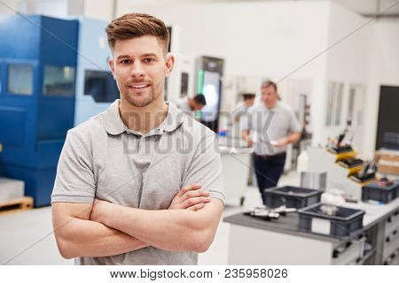 Portrait Of Male Engineer On Factory Floor Of Busy Workshop