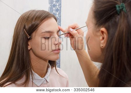 The Process Of Creating Makeup. Makeup Artist Working With A Brush On The Face Of The Model.