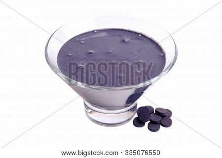 Black Yogurt In A Bowl With Activated Carbon Tablets Isolated On A White Background.