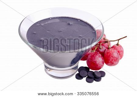 Black Yogurt In A Bowl With Red Grapes And Activated Carbon Tablets Isolated On A White Background.